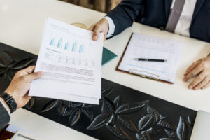 Male Accountant Handing Out Report Across Table