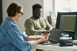 coworkers at computers at the office, protected with backup and disaster recovery plans